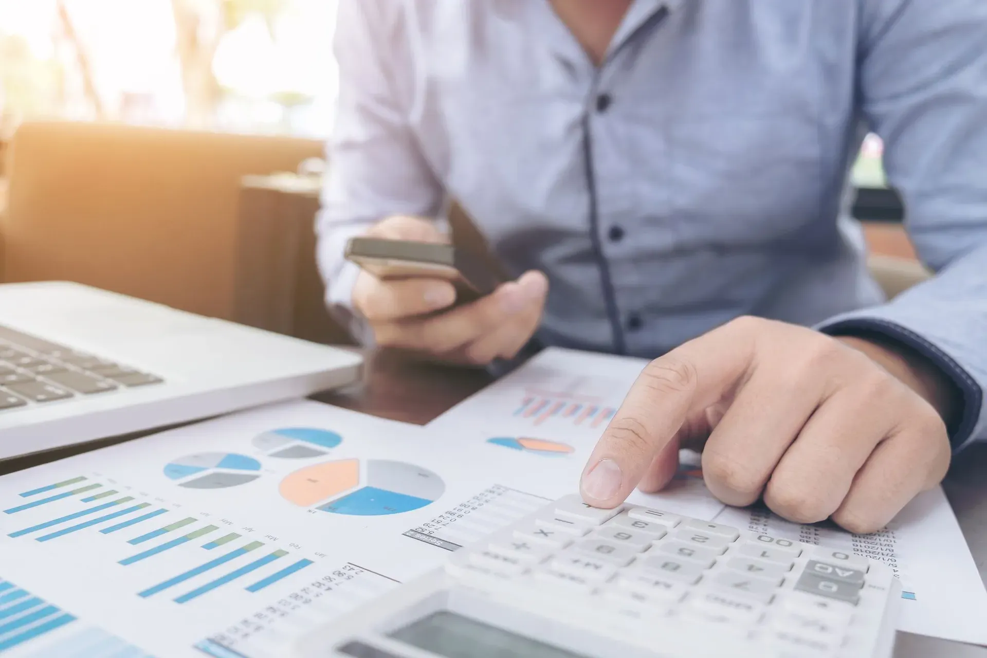 Man holding phone pointing to graph